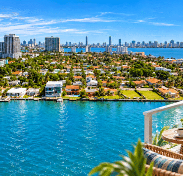 Photo composite of North Bay Village waterfront and Biscayne Bay, with a furnished balcony in the foreground.