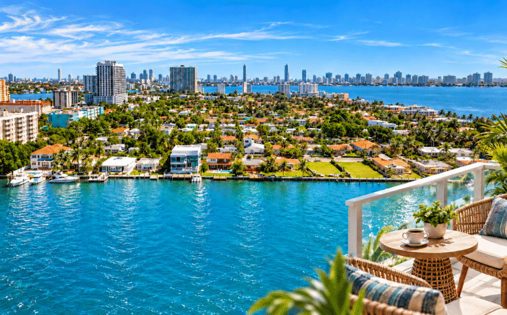 Photo composite of North Bay Village waterfront and Biscayne Bay, with a furnished balcony in the foreground.
