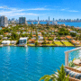 Photo composite of North Bay Village waterfront and Biscayne Bay, with a furnished balcony in the foreground.