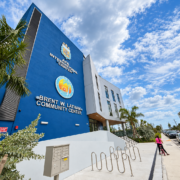Angled exterior view of the Brent W. Latham Community Center and AFA International Center in North Bay Village, with palm trees and bicycle racks.