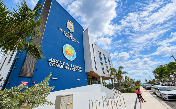 Angled exterior view of the Brent W. Latham Community Center and AFA International Center in North Bay Village, with palm trees and bicycle racks.