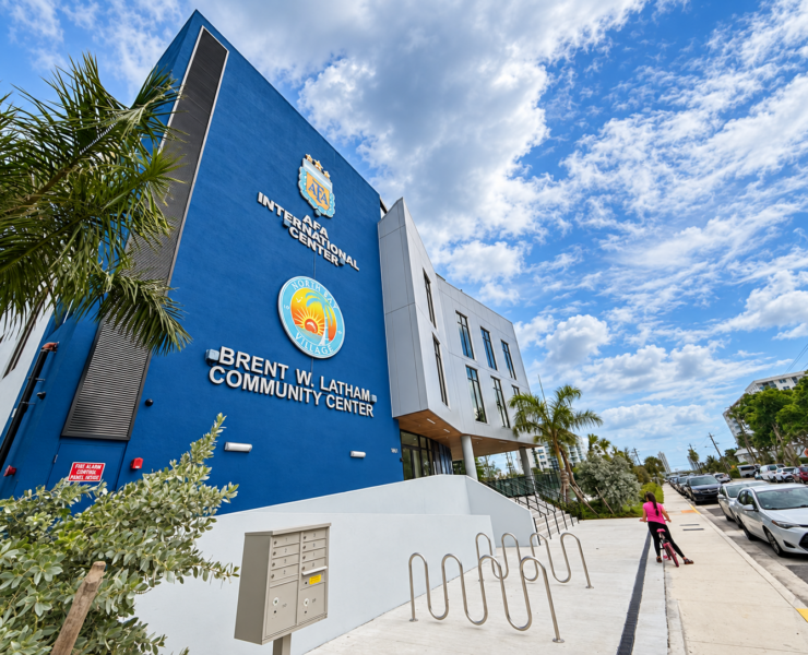 Angled exterior view of the Brent W. Latham Community Center and AFA International Center in North Bay Village, with palm trees and bicycle racks.