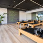Modern Pilates studio with wooden reformer machines, mirrored walls, natural light, and waterfront views.
