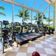Cardio equipment at Treasure Drive Fitness in North Bay Village, beside large windows overlooking palm trees and the marina.