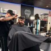 Barber cutting a client’s hair at a North Bay Village barbershop in Grandview Palace’s commercial area.