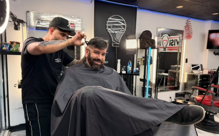 Barber cutting a client’s hair at a North Bay Village barbershop in Grandview Palace’s commercial area.