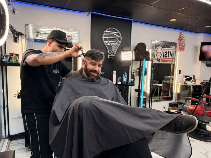 Barber cutting a client’s hair at a North Bay Village barbershop in Grandview Palace’s commercial area.