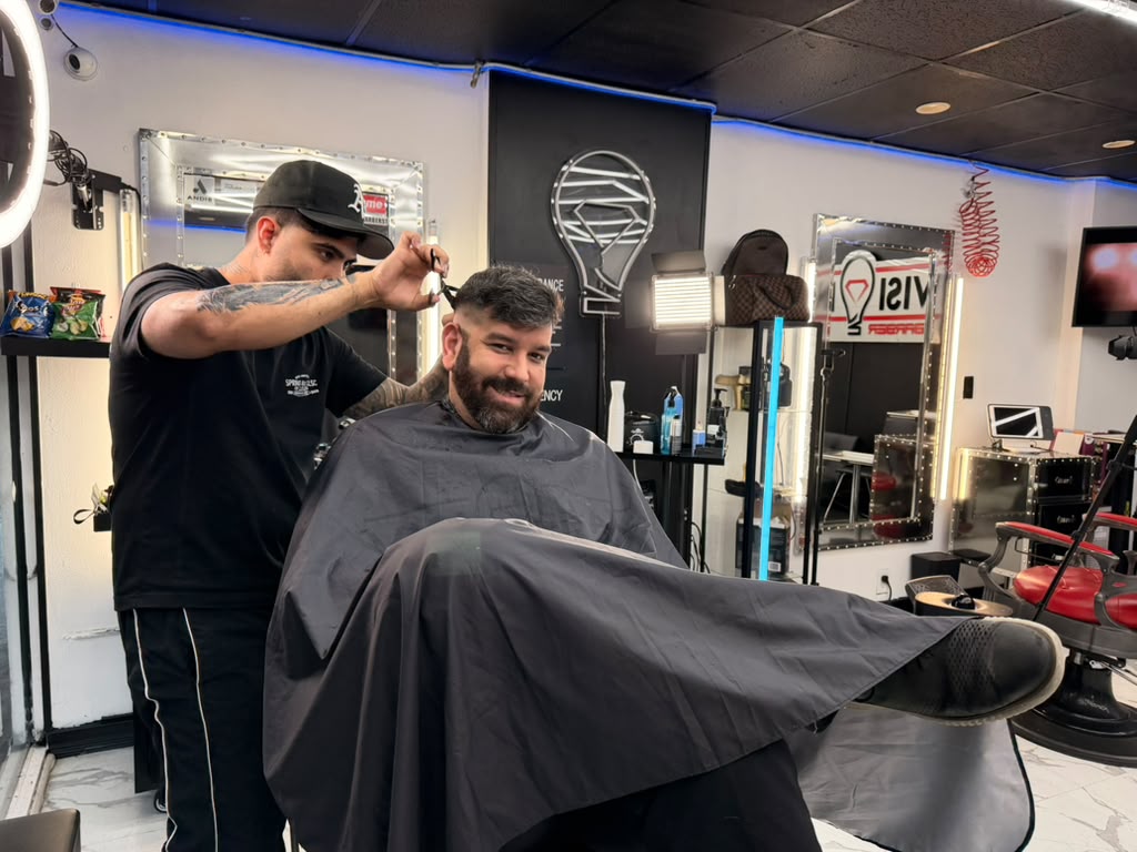 Barber cutting a client’s hair at a North Bay Village barbershop in Grandview Palace’s commercial area.